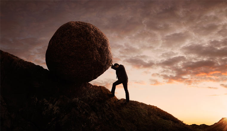 A picture of a person pushing a large rock up a hill