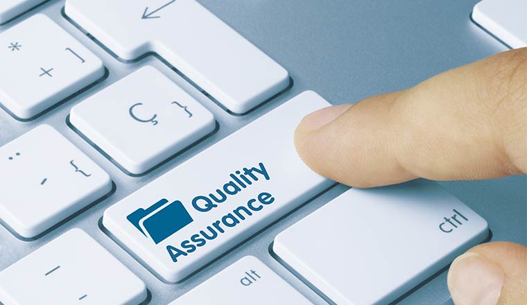 A photo of someone pressing a button that says "quality assurance"