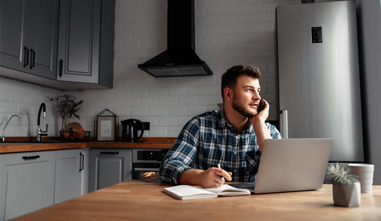 A picture of an agent working at home on kitchen table with laptop