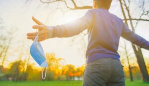 A picture of a man standing outside holding a mask