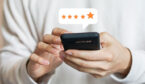 A picture of a person holding a mobile phone with a star rating feedback icon