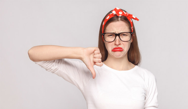 A picture of a lady frowning with her thumb pointing down