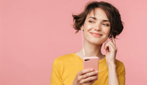 A picture of a woman listening to music with earphones on mobile phone.