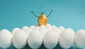 A picture of a golden egg wearing standing above a group of white eggs