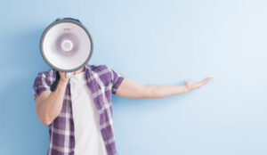 A picture of a person gesturing whilst using a megaphone