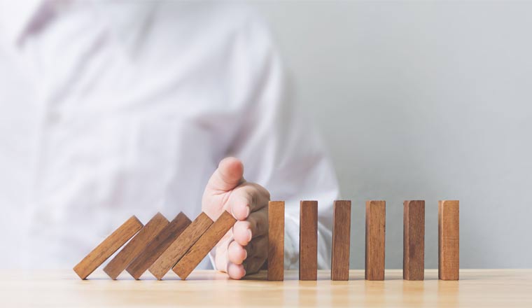 A picture of a hand stopping dominos from falling