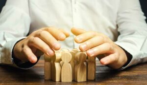 A picture of a pair of hands shielding a group of wooden figurines