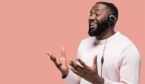 A call centre worker with headphones in casual wear standing on a pink isolated background