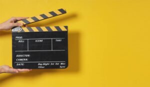 Hand is holding clapper board or movie slate on yellow background