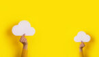 Two hands holding paper cloud over yellow background