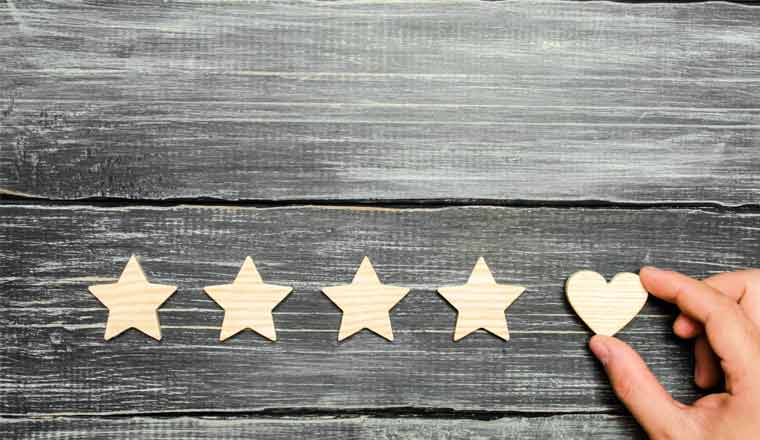 A hand adding a heart to a rating system on wooden background