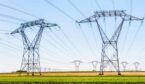 Panoramic view of a row of electricity pylons in the countryside with dozens of other pylons in the distance.