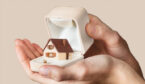 A a pair of hands holding a house inside a ring box
