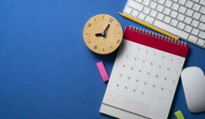 close up of calendar, alarm clock and accessories on the blue table background