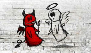 Angel and devil fighting; doodle drawing on white brick wall