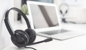 A picture of a headset in the foreground and a laptop in the background