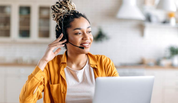 A picture of a person on a laptop wearing a headset