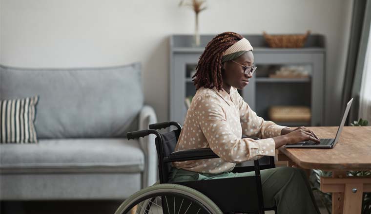 A person in a wheelchair working on a laptop from home