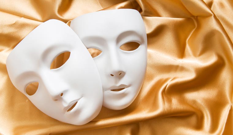 Theatre concept with the white plastic masks on gold fabric