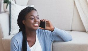 Person on mobile phone sat in front of a sofa