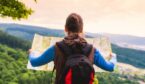 Traveler with backpack checks map to find directions in wilderness area