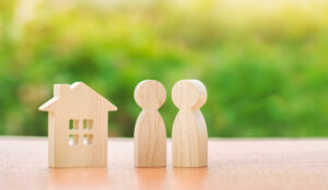 Two wooden figures of people and a house on a nature background