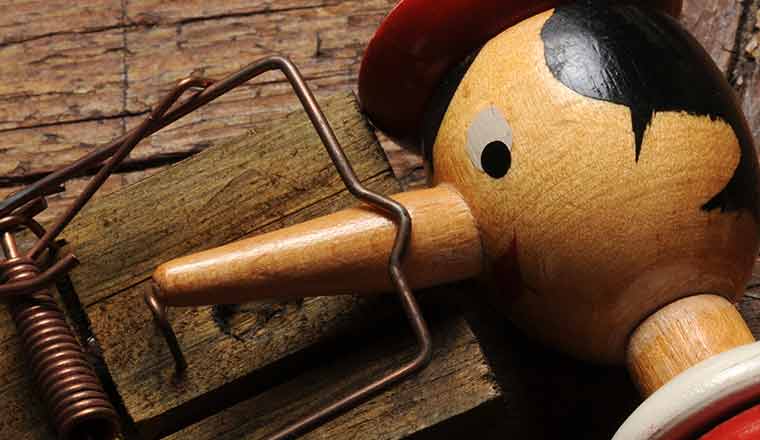 A wooden doll with a long nose stuck in a mouse trap