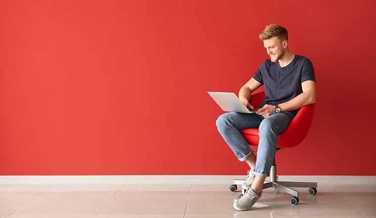 Person with laptop sitting on chair near colour wall