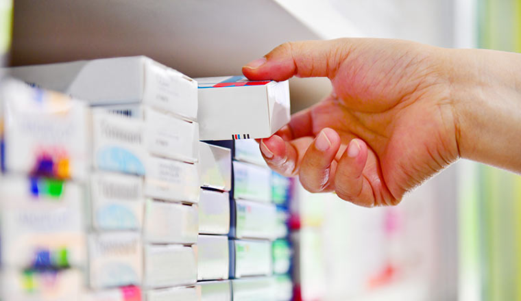 Closeup pharmacist hand holding medicine box in pharmacy drugstore.