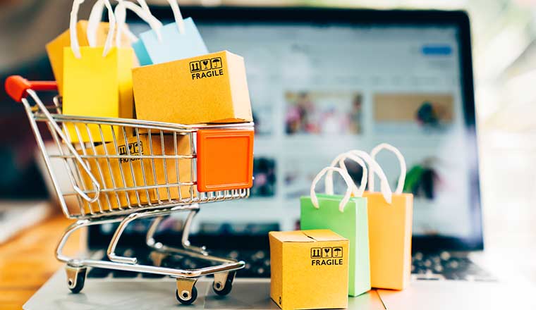 Product package boxes and shopping bag in cart with laptop computer which web store shop on screen