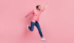 Person jumping having fun success isolated over pink pastel color background