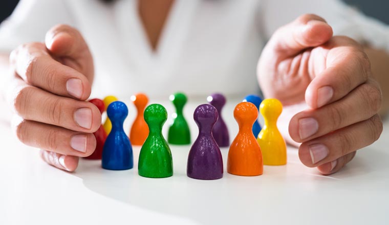 A picture of hands possessively guarding a series of coloured pawns