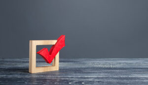 A red tick in a wooden box on a grey background