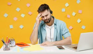 Unhappy call centre agent in front of yellow wall covered in post it notes