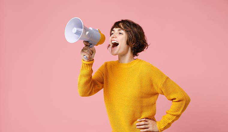 Person on megaphone in front of pink background