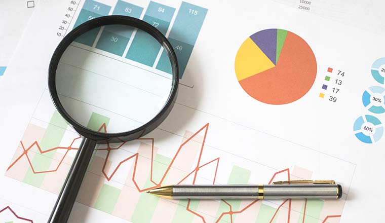 A magnifying glass an pen on business charts