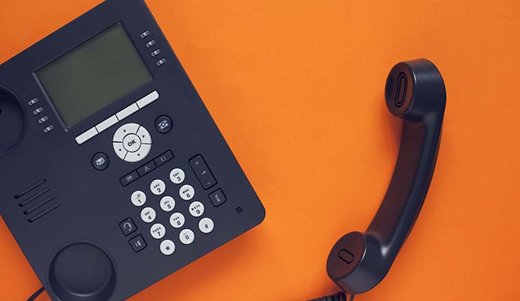 An office phone isolated on an orange background
