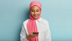 Person focussed on phone in front of blue background