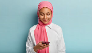 Person focussed on phone in front of blue background