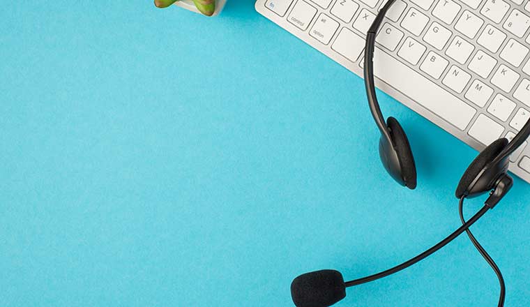 Top view photo of black headphones with microphone on white keyboard