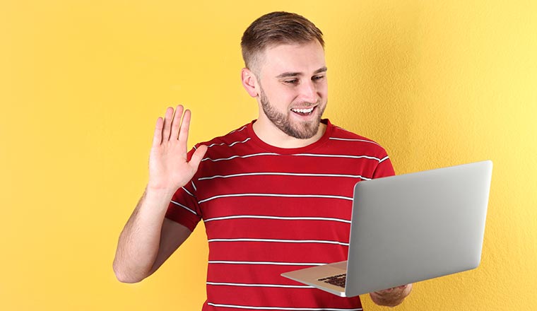 Person using video chat on laptop against color background