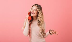 Person on landline phone on pink background