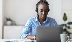 Phone operator in headset working with laptop in office