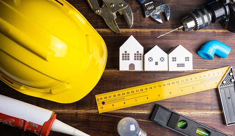 Paper white house toy and construction tools on wooden background