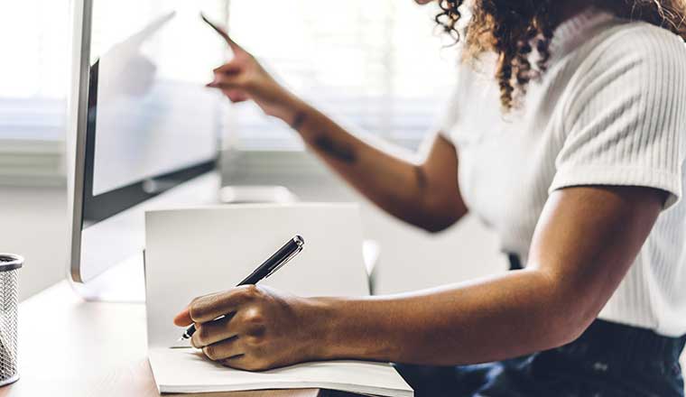 Person working from home and making notes from a screen