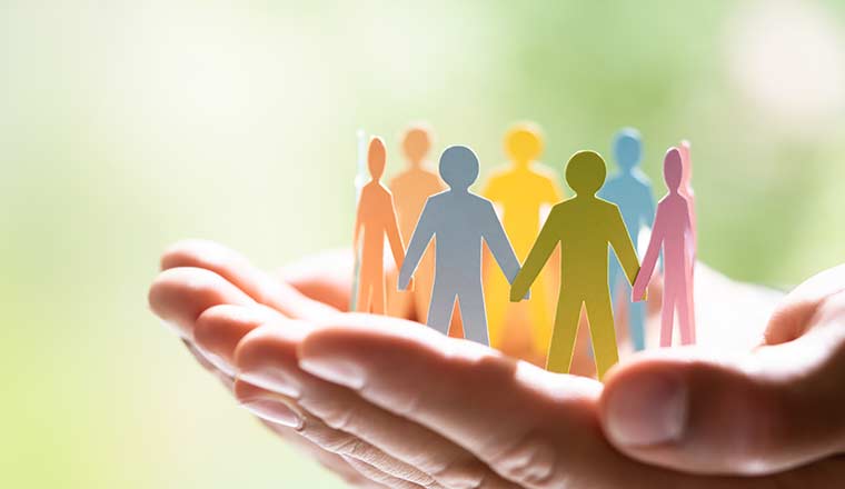 A hand holding paper figures grouped as a team