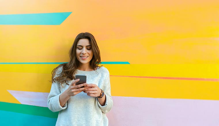 Person with phone against coloured wall