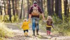 An adult walking in the woods with two children