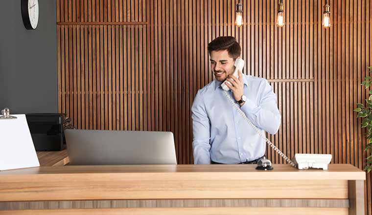 Receptionist talking on phone at desk in lobby