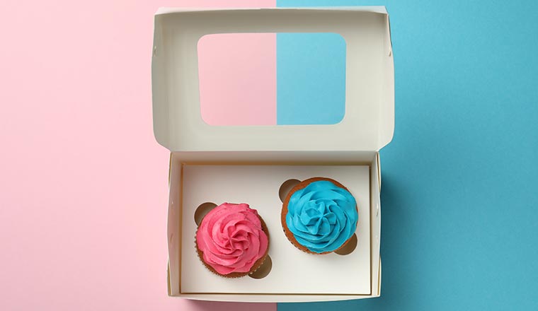 Box with two different cupcakes on color background